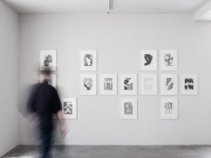 Bewegte Person im Ausstellungsraum mit Zeichnungen an der Wand