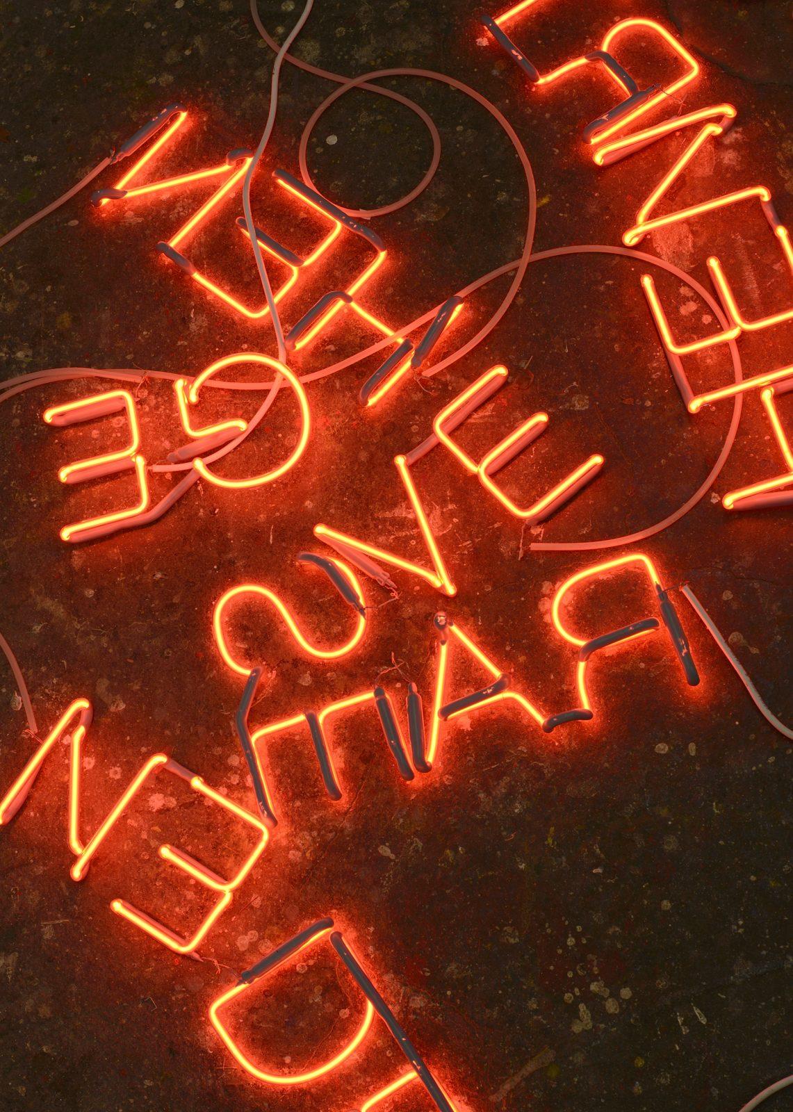 Installation von rot leuchtenden Buchstaben auf schwarzem Intergrund