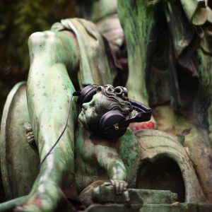 Eine Statue mit einem Erwachsenen und einem kleinen Engel, der Engel trägt Kopfhörer.