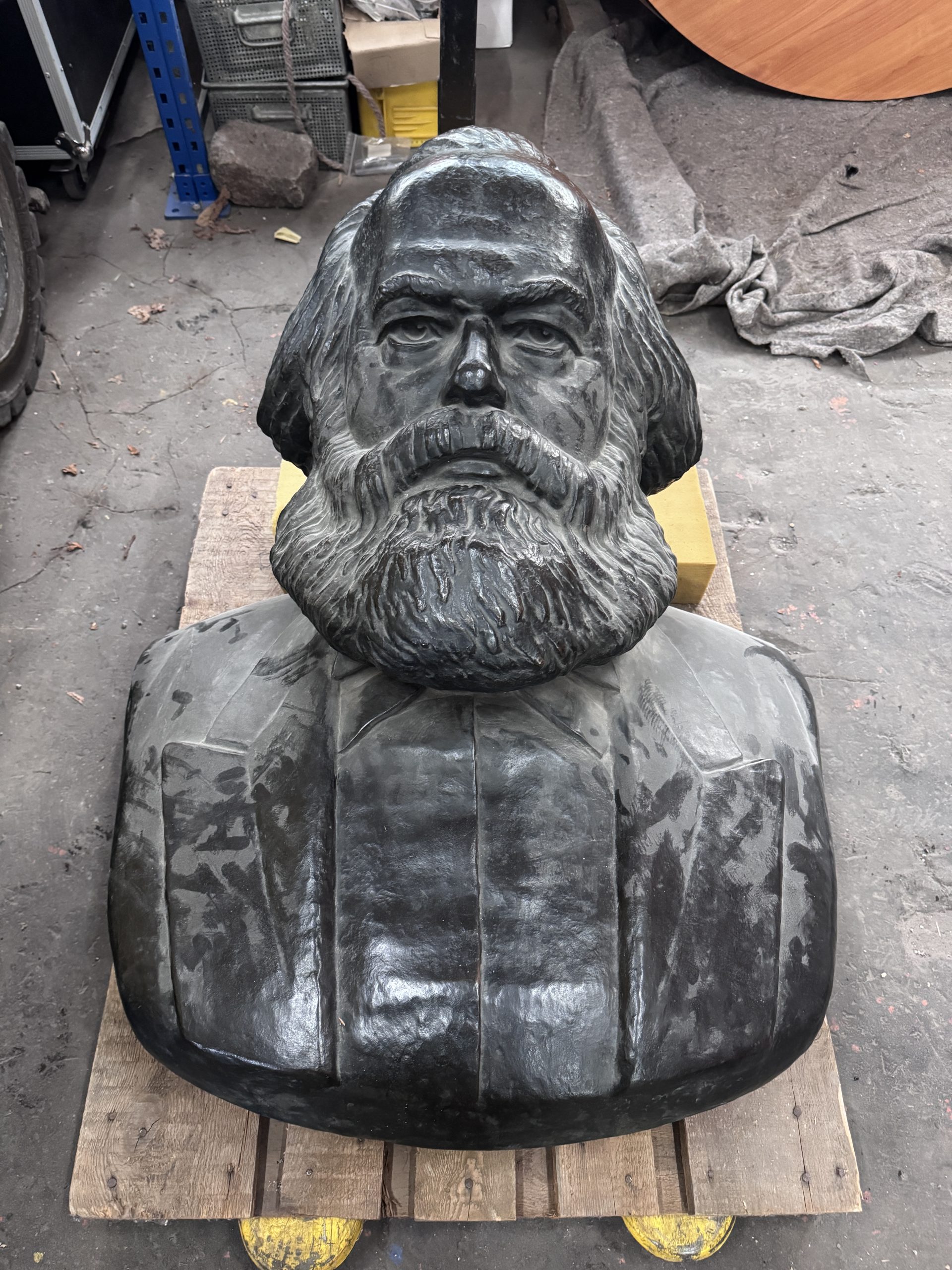Eine Büste von Karl Marx aus Metall liegt auf einer Palette.