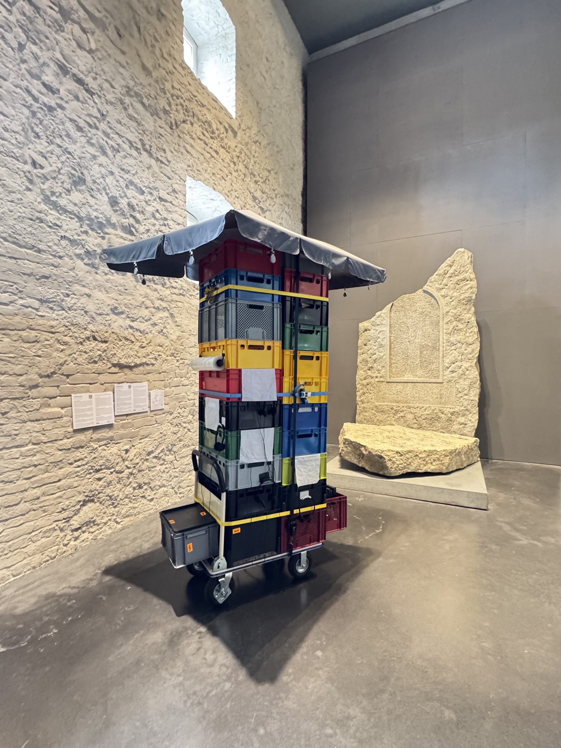 Eine Skulptur aus Plastikkästen, die in der Ausstellung Enthüllt. Berlin und seine Denkmäler steht.