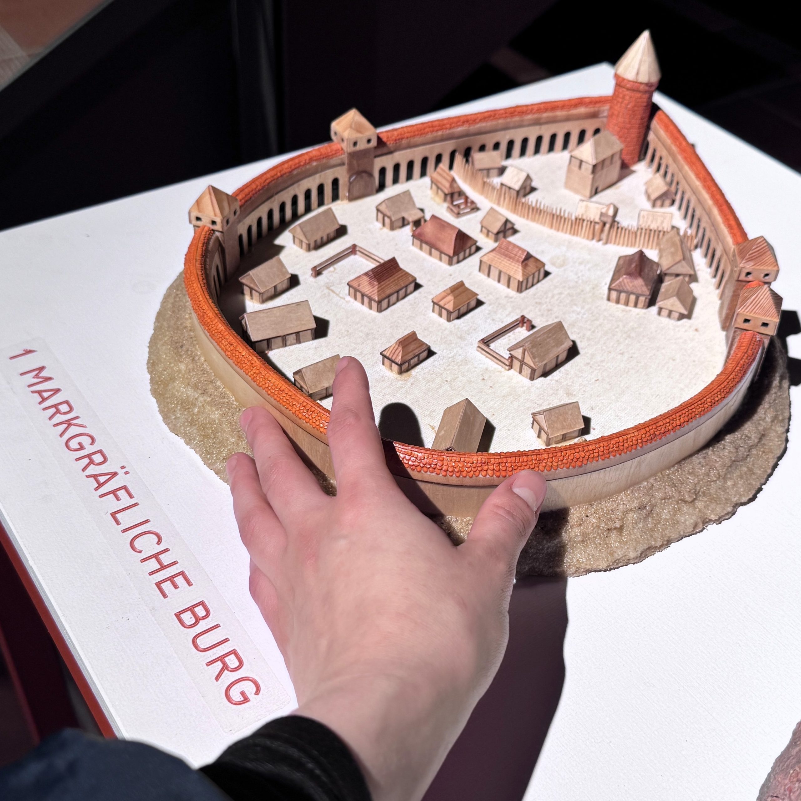 Eine Hand berührt das Tastmodell einer Burg